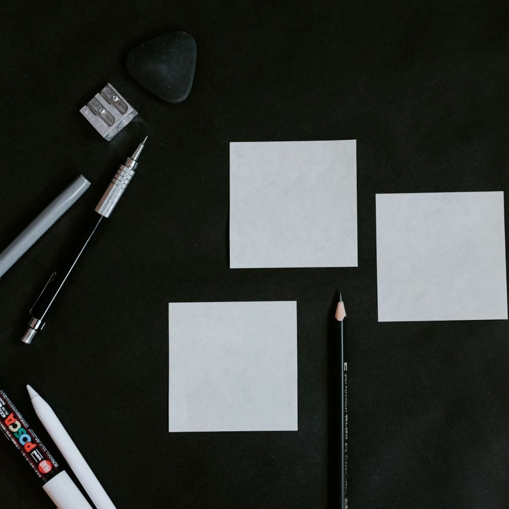 mesa negra cubierta con cartulas blancas y lapices